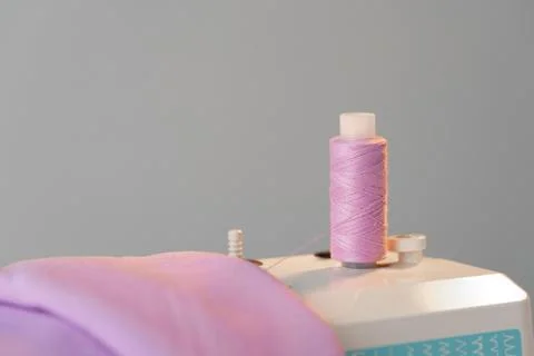 View of a sewing machine with a spool of pink thread placed on top Stock Photos