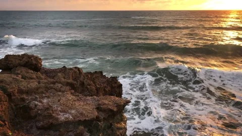 View from the shore of large sea waves crashing against rocks in a sunset time Stock Footage 147377473