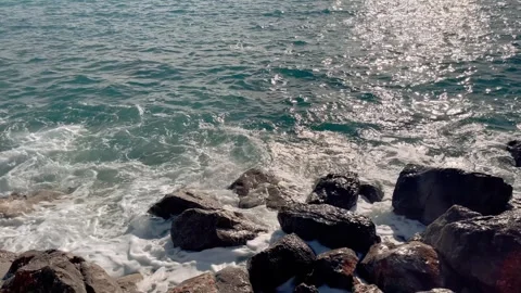 View from shoreline of beach with pebbles. Waves crash against the coastal rocks Stock Footage 257108843