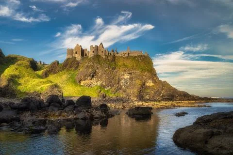View from a shoreline on Dunluce Castle nested on the edge of cliff, part of  Foto stock