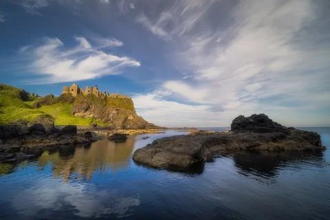 View from a shoreline on Dunluce Castle nested on the edge of cliff, Northe.. Stock Photos