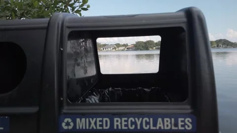 View shot through a double Trash and Recycle Trash can by the water. Stock Footage 250648532
