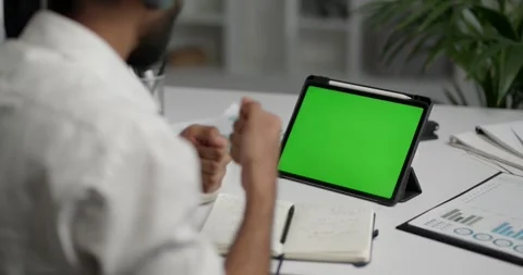 View from the shoulder of a businessman using tablet with green mock-up screen Video stock 243525165