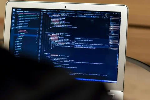 View from the shoulder to the laptop screen with the program code. Compilatio Foto stock