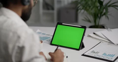 View from the shoulder of man using tablet with green mock-up screen. Stock Footage 243524873