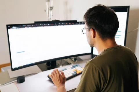 View from shoulder of programmer in glasses concentrating on complex task Stock Photos