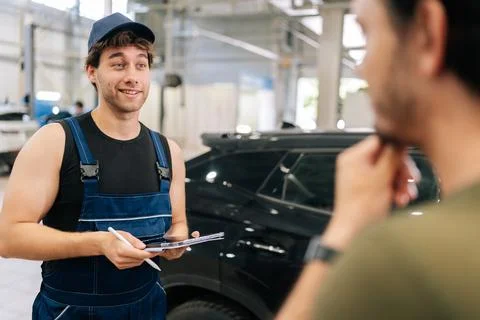 View from shoulder of unrecognizable man client to mechanic male in uniform Stock Photos