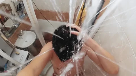 View from a shower head to man taking shower in the bathroom. Slow motion Stock Footage 135461889