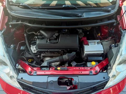The view shows the engine area of a red car parked in a garage. Various mecha Stock Photos