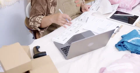 View shows laptop, invoice sheet, barcode device, parcel box set, shibori fabric 스톡 동영상 330591045
