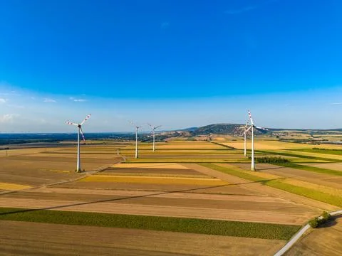 The view shows wind turbines in an open field with various crop patterns. The Stock Photos