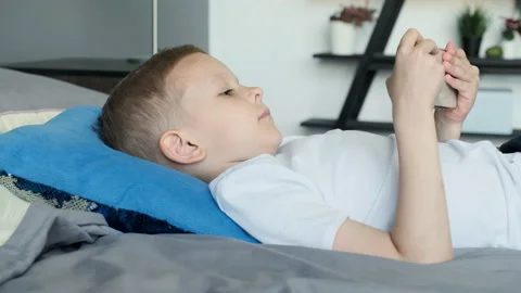 View from the Side A Child Boy Looks at the Phone Screen Plays a Game Stock Footage 156244801