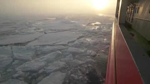 View from side of icebreaker back. Sun behind in fog. Pieces of ice float out Stock Footage 258014358
