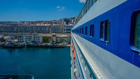 View from the side of a large cruise ship docked in a vibrant coastal harbor Stock Photos