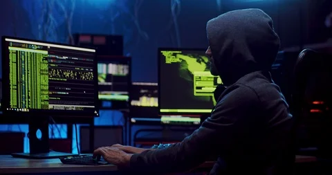 View from the side on the man in a hood working as a hacker at the computer in 스톡 동영상 124347924