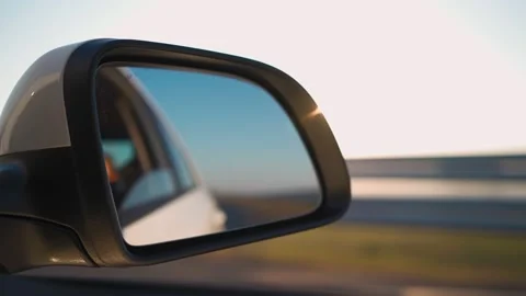 View in side mirror car that is driving fast on highway in sunset light. Stock Footage 157537611