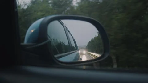 View in the Side Mirror of a Car that is Driving on the Urban Highway at dusk Stock Footage 248843596