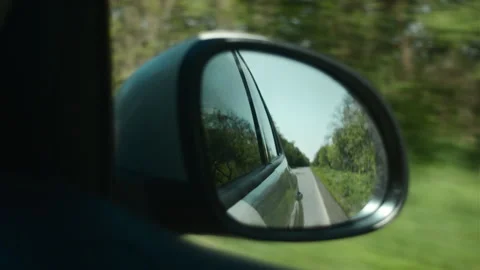 View in side mirror of car that is driving fast on highway in warm sunny light Stock Footage 275037054