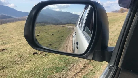 View in the side mirror, the car moves off-road in the Caucasus Stock Footage 102459338