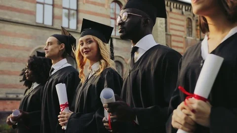 View from the side on the multi ethnical graduates standing in a line and blonde Stock Footage 83602716