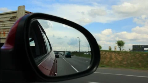 View in the side rear view mirror of a car driving a red car Stock Footage 171408502