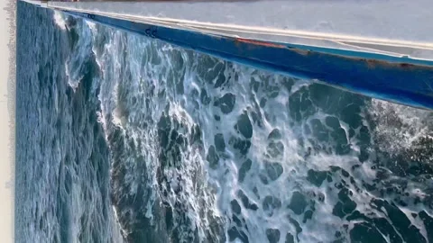 View from the side of the ship to the sea foam - Vertical stock video Stock Footage 239640895