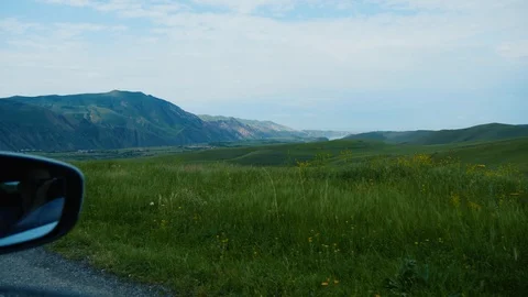 View from the side window of the car moving along hilly valley in mountains 스톡 동영상 94425330