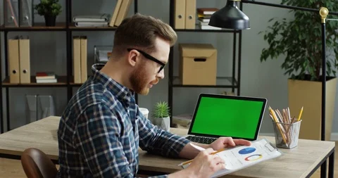View from the side on the young man in the glasses sitting at the office desk Stock Footage 89950499