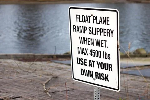 View of sign Float Plane Ramp Slippery When Wet, Use At Your Own Risk Stock Photos
