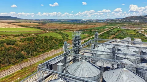 View of silos and train tracks near fields in a rural area under a blue sky with Stock Footage 341074531