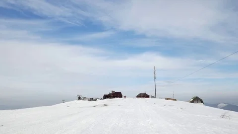 View on the ski base from mountain. People drive by the camera on a snowmobile. Stock Footage 72831569