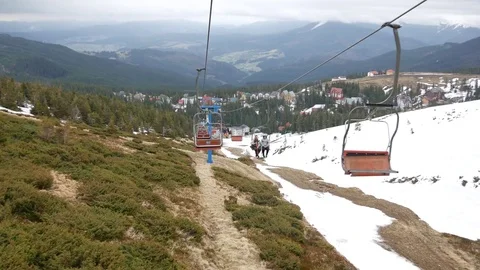 View from a ski lift that is going down the mountain over the ski pistes. Stock Footage 77228908