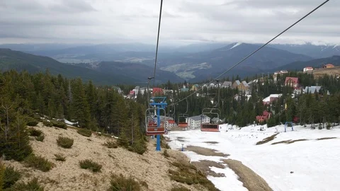 View from a ski lift that is going down the mountain over the ski pistes. Stock Footage 77229034