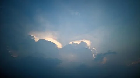 A view of the sky with clouds illuminated by sunlight from behind the clouds. Stock Photos