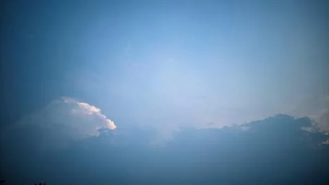 A view of the sky with clouds illuminated by sunlight from behind the clouds. Stock Photos