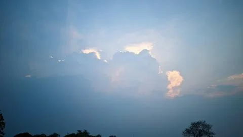 A view of the sky with clouds illuminated by sunlight from behind the clouds. Stock Photos
