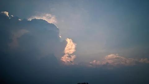 A view of the sky with clouds illuminated by sunlight from behind the clouds. Stock Photos