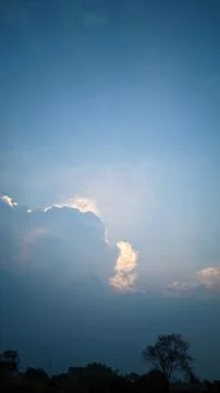 A view of the sky with clouds illuminated by sunlight from behind the clouds. Stock Photos