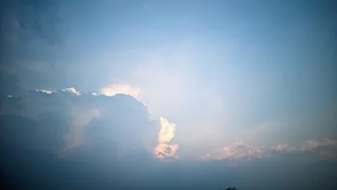 A view of the sky with clouds illuminated by sunlight from behind the clouds. Stock Photos
