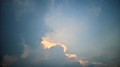 A view of the sky with clouds illuminated by sunlight from behind the clouds. Stock Photos