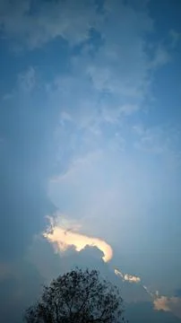 A view of the sky with clouds illuminated by sunlight from behind the clouds. Stock Photos