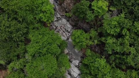 View from the sky of a group of unrecognizable people get ready to go canyoning. Stock Footage 201525446
