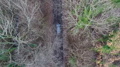 View from the sky: a station wagon makes its way through a muddy, puddle-st.. Video stock 260732976