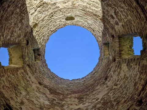 View of the sky through an old and ruined brick building with a round roof 写真素材