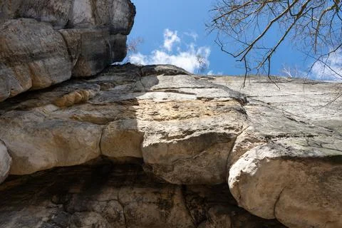 View up to sky through rocky formation and trees branches Stock Photos