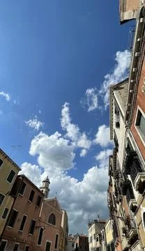 View of the sky with white clouds and Venetian houses. Stock Photos