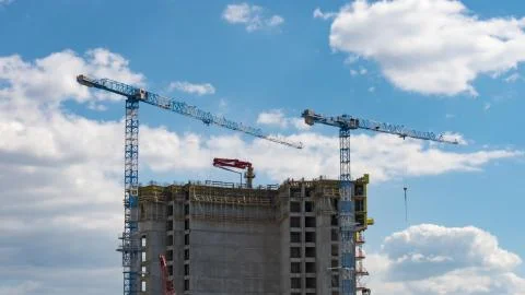 View of skyscraper building construction with cranes on the roof. Stock Photos