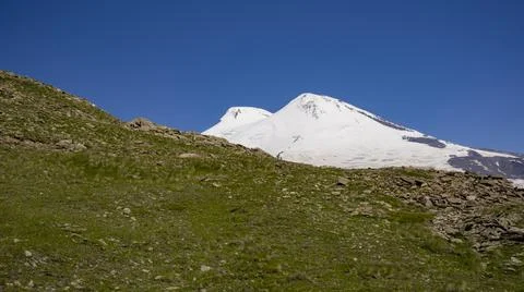 View from the slope of Mount Cheget to the two peaks of the Elbrus volcano while Stock Photos