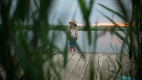 View in slow motion through green reeds of european blond girl 7-8 fishing with Stock Footage 91223074