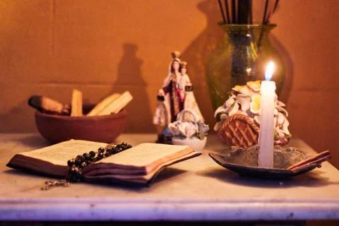 View of a small home altar with lit candles, a Bible, a cross, decorations Stock Photos